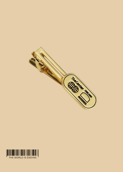 THE CENTER OF ORDER AND EXPERIMENTATION x THE TIE BAR THE INDICATOR BRUSHED GOLD TIE BAR